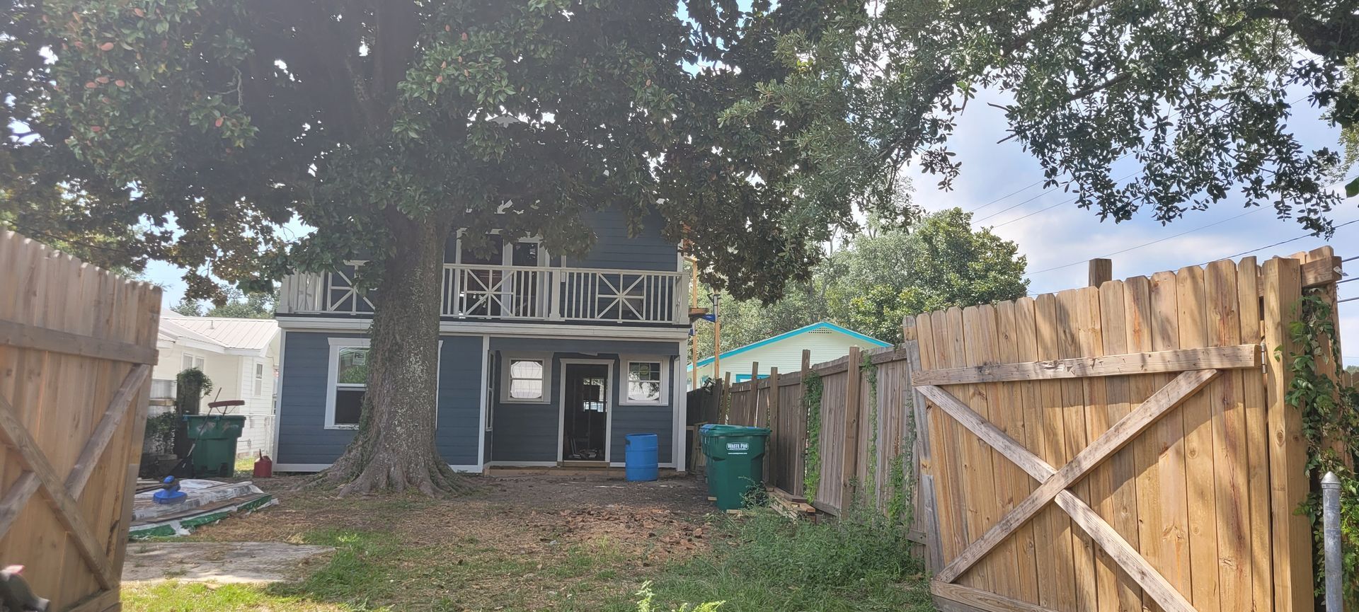 A house with a wooden fence and a tree in front of it.