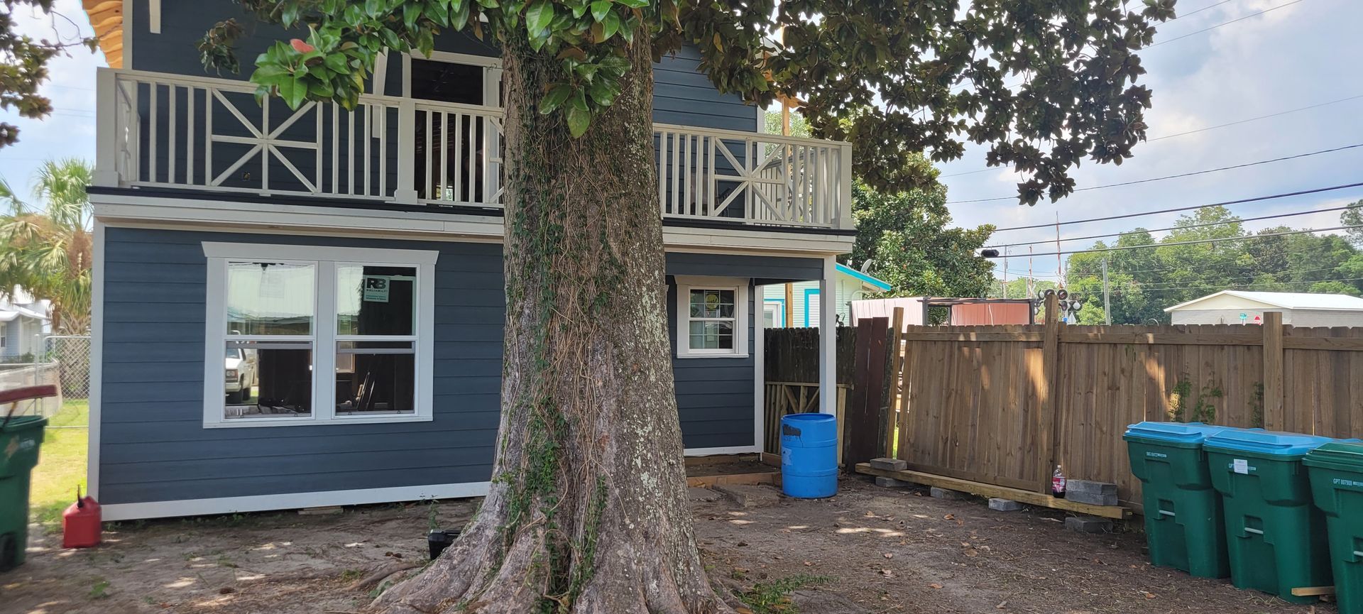 The back of a house with a tree in front of it.