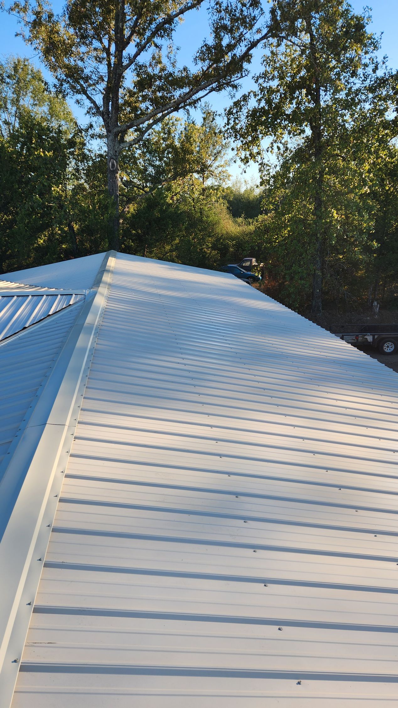A white roof with trees in the background and a blue sky.