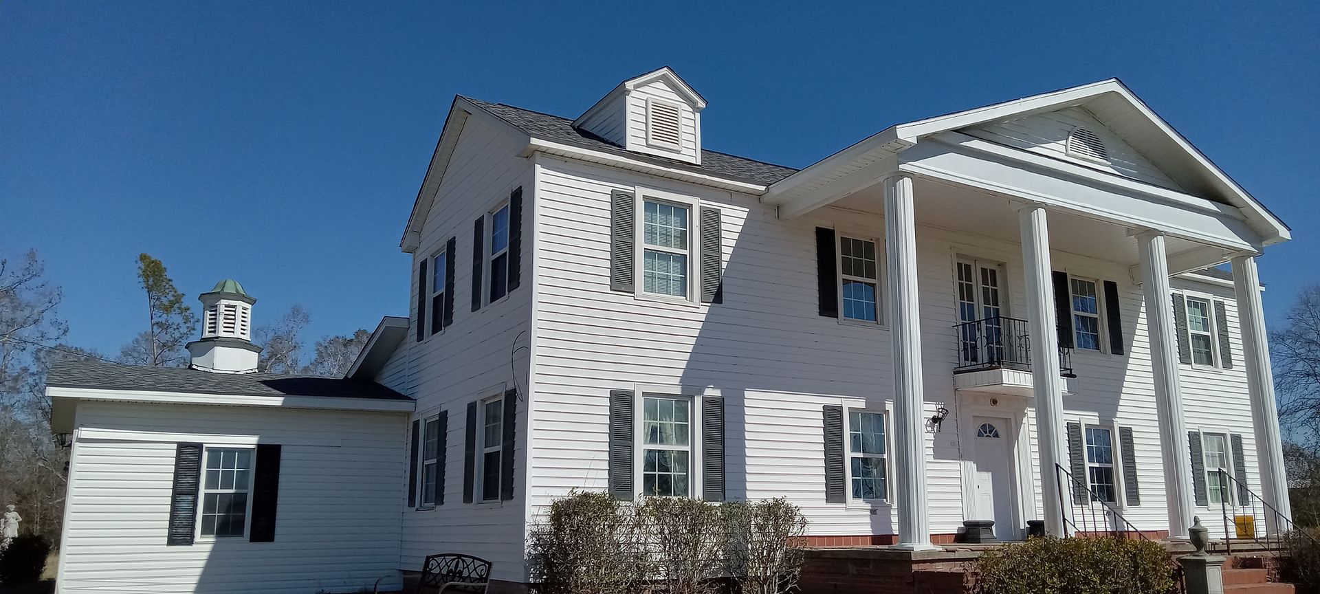 A large white house with a porch on a sunny day.