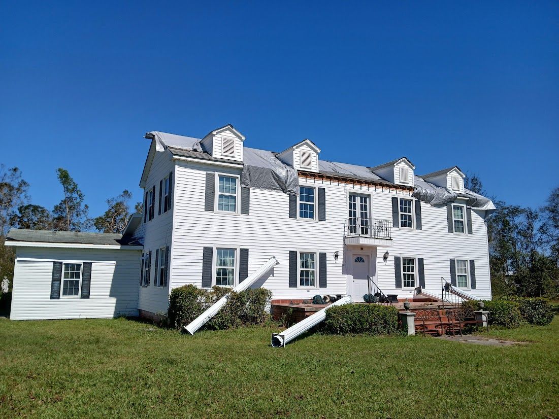 A large white house is sitting in the middle of a grassy field.