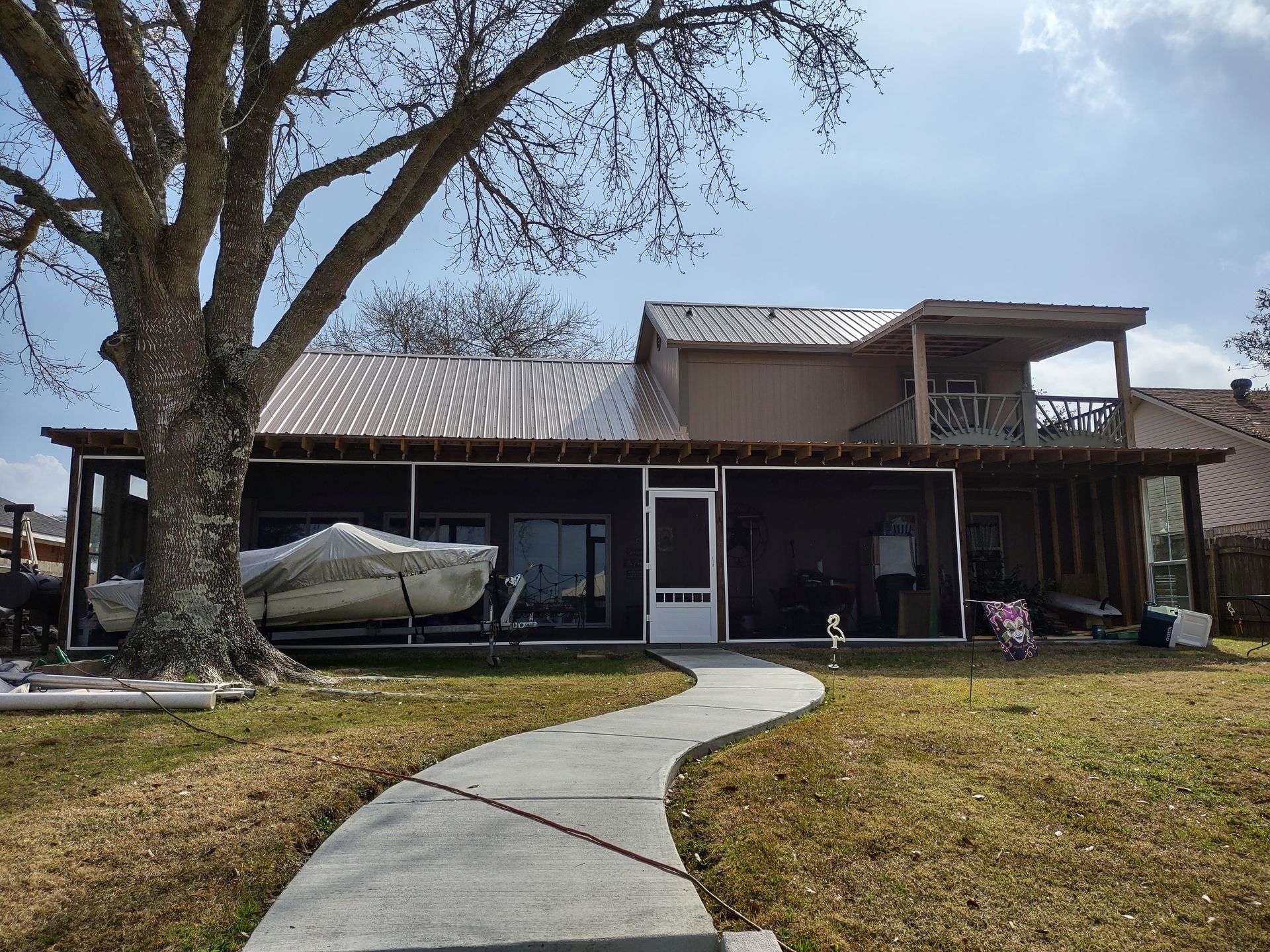 A house with a screened in porch and a boat in the backyard.