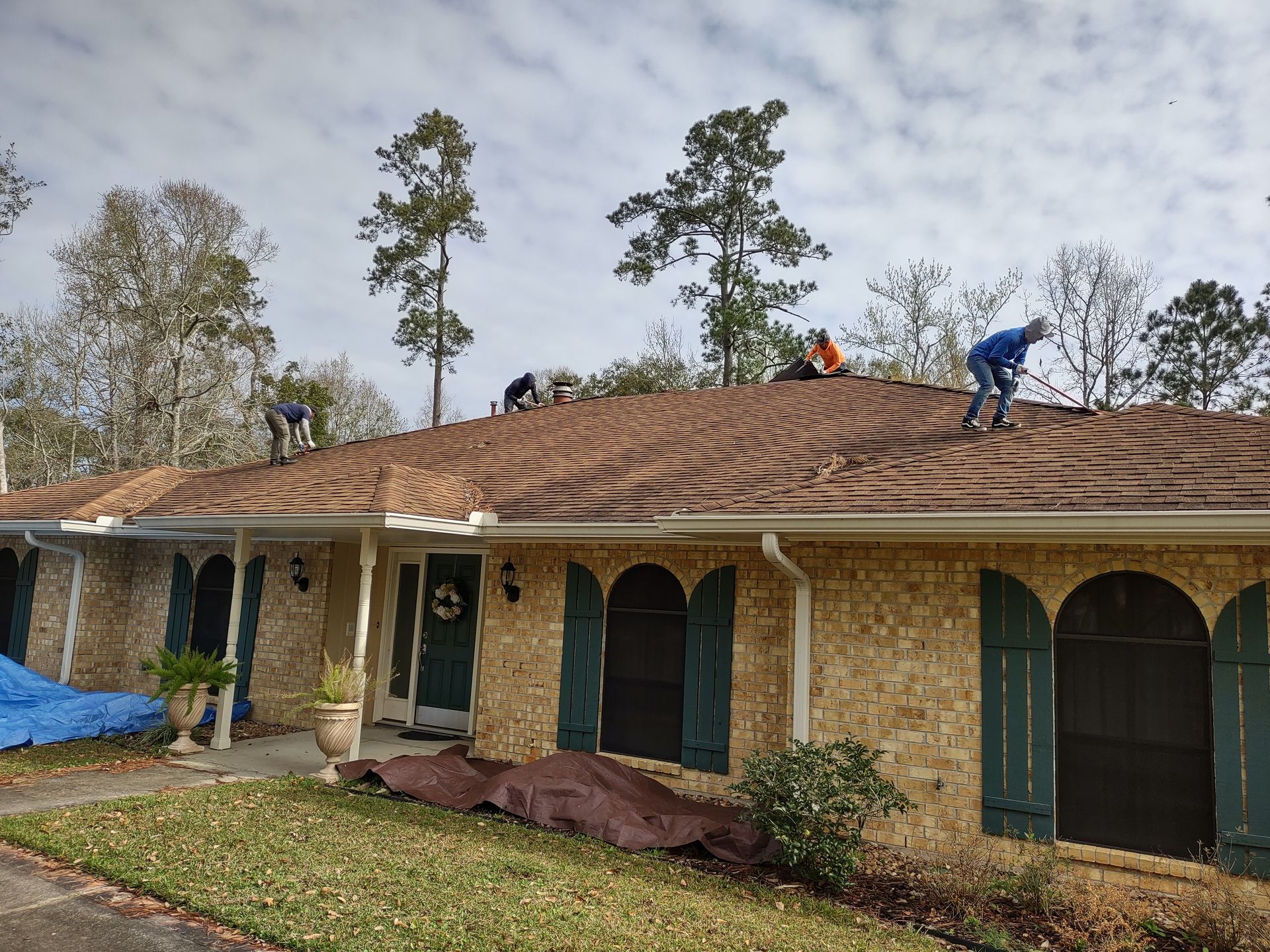 A group of people are working on the roof of a house.