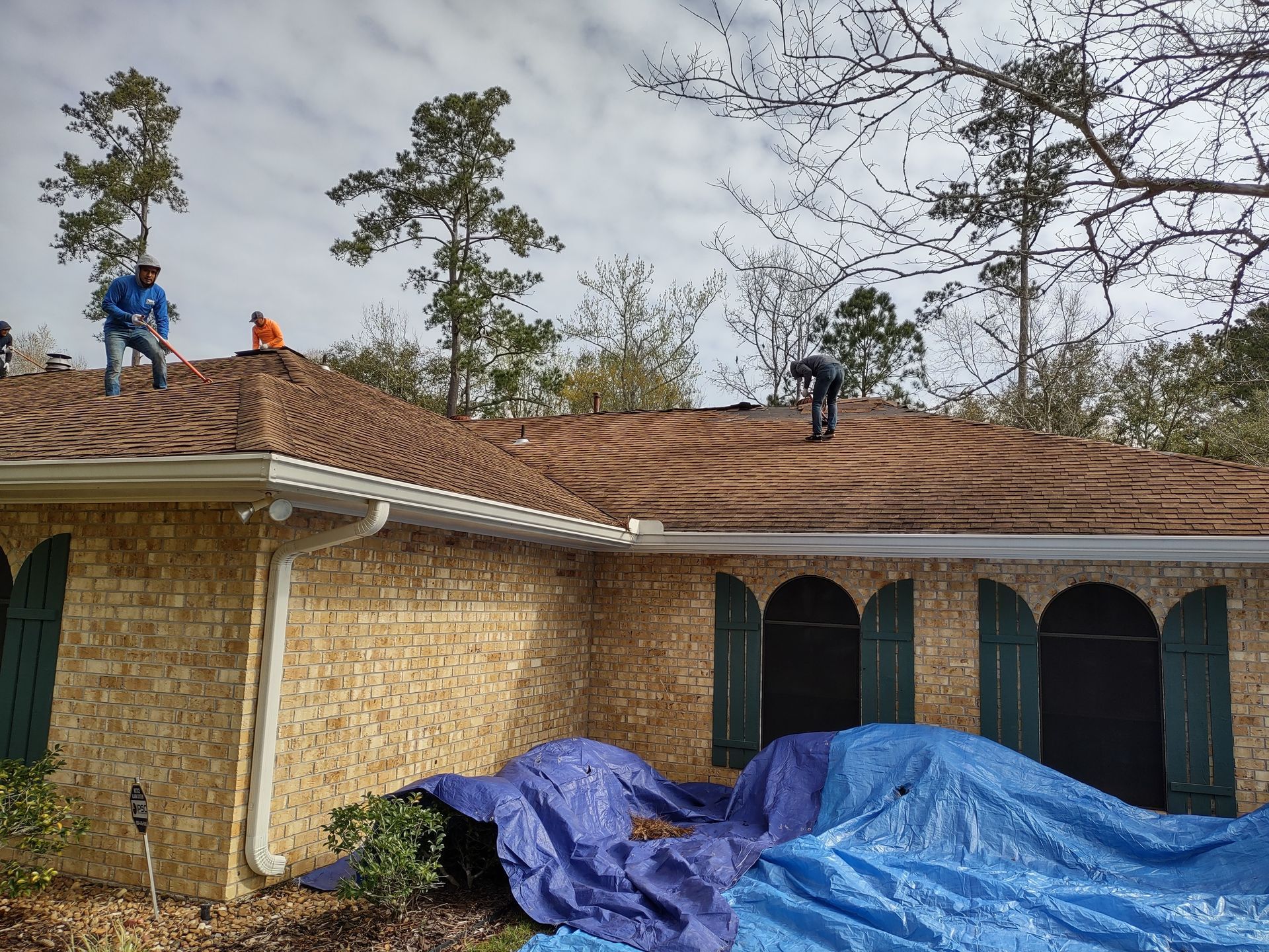 A group of men are working on the roof of a house.