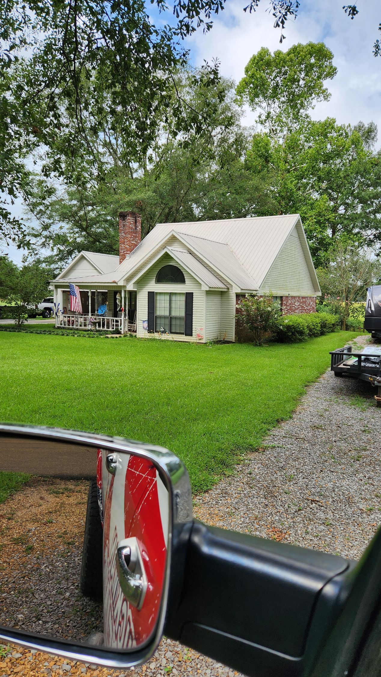 A house is reflected in a rear view mirror of a car.