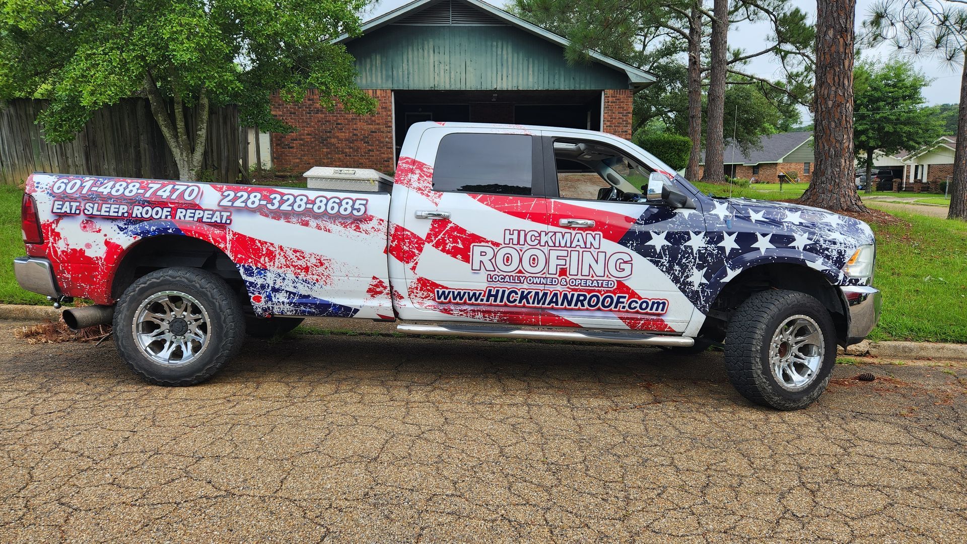 A red white and blue truck is parked in front of a house.