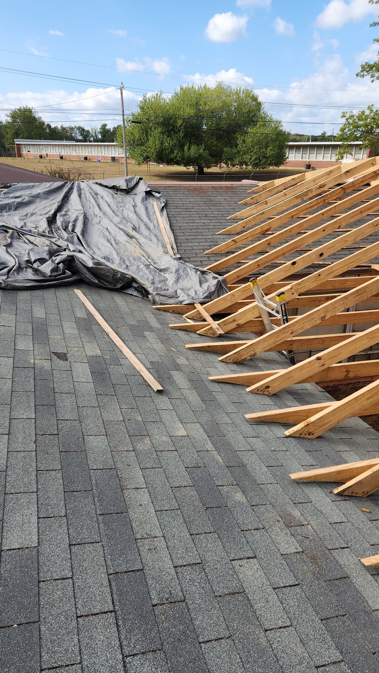 A roof is being built with wooden beams and shingles.