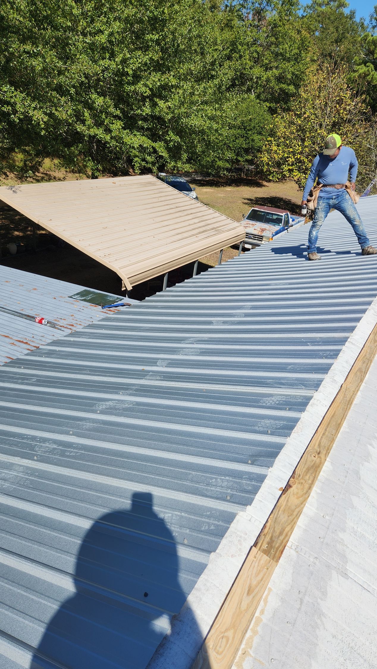 A man is standing on top of a metal roof.