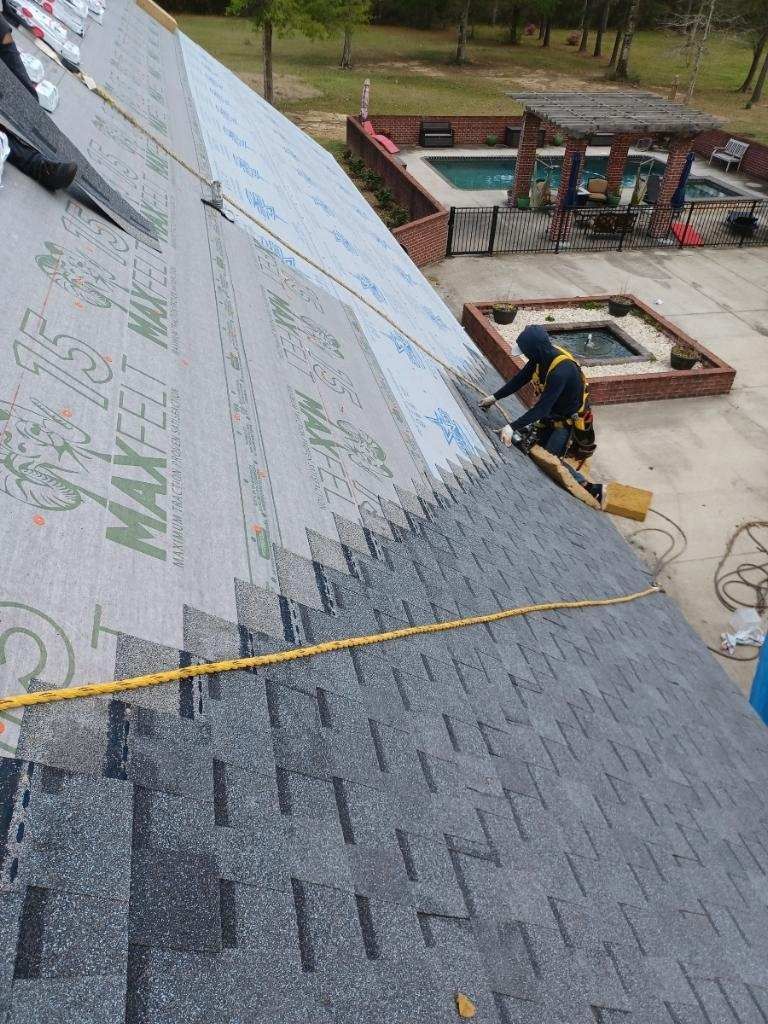 A man is working on a roof with a pool in the background.