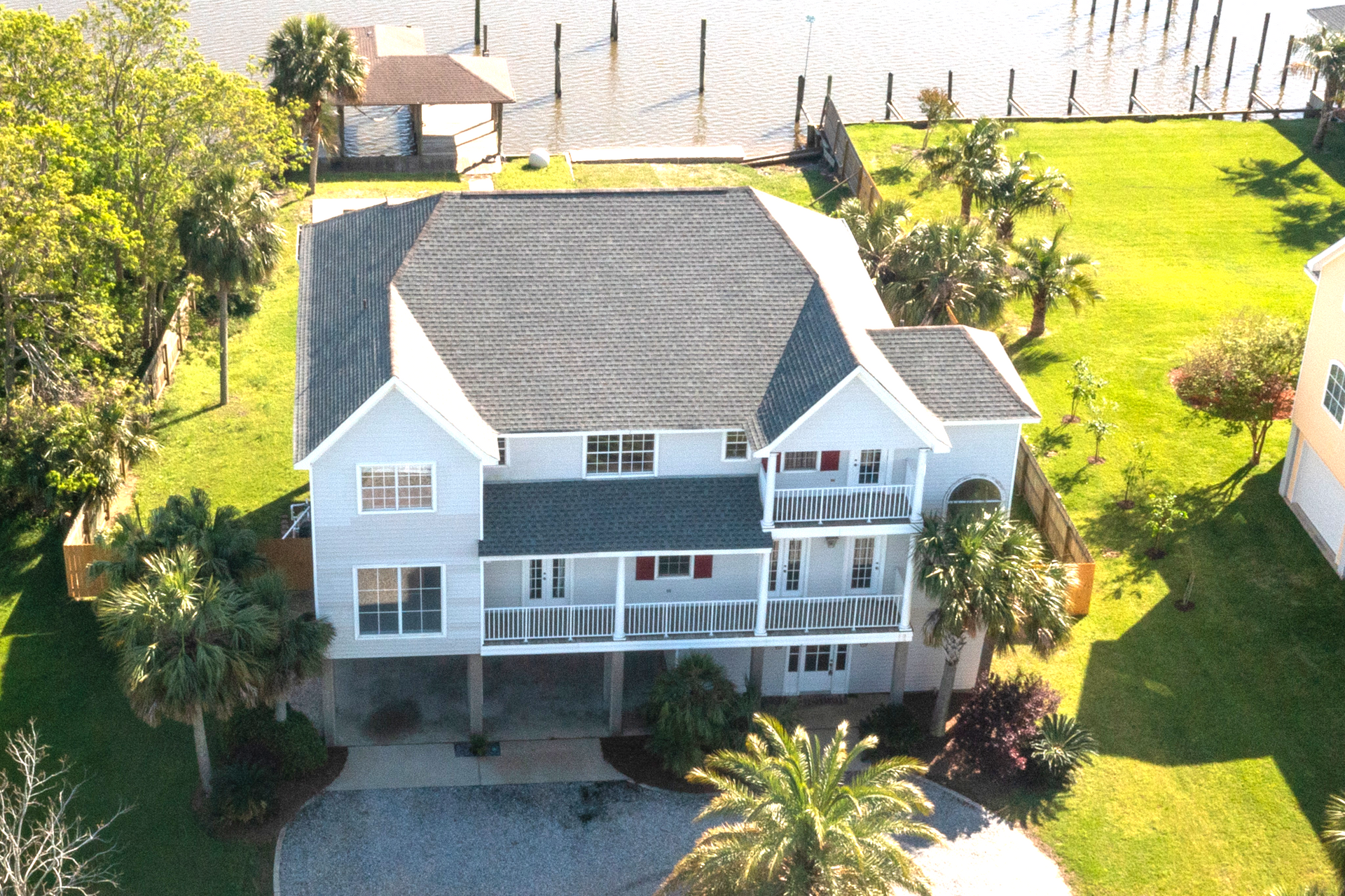 An aerial view of a large white house surrounded by palm trees