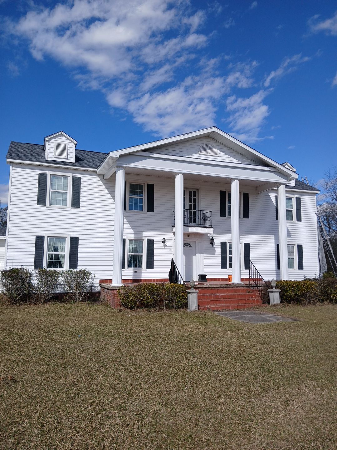 A large white house with a clock on the top of it