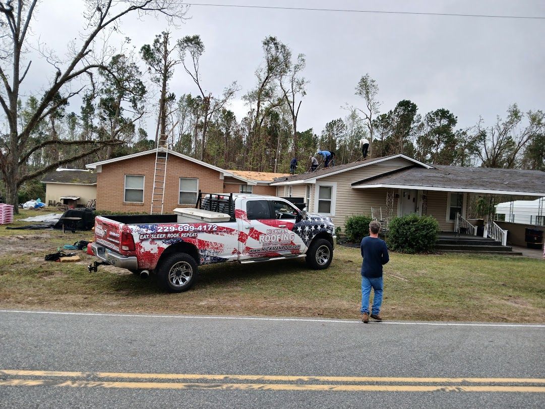 A truck is parked in front of a house that has been damaged by a hurricane.