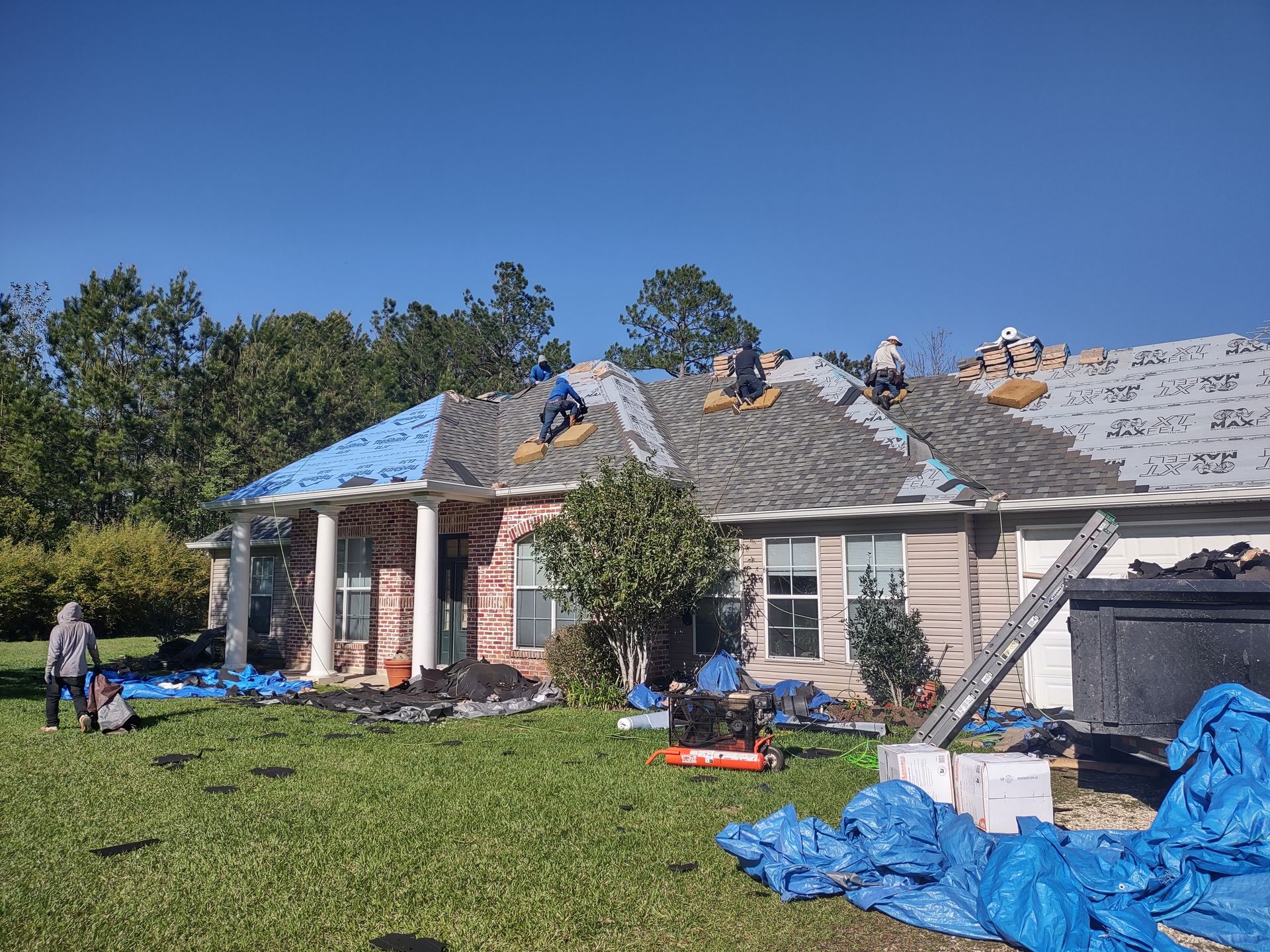 A group of people are working on the roof of a house.