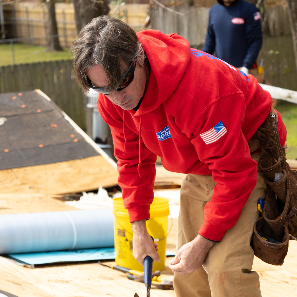 A man in a red hoodie is working on a roof
