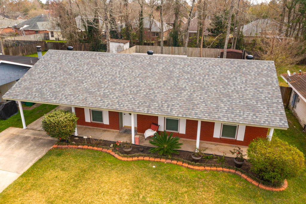 An aerial view of a house with a gray roof and a large lawn.