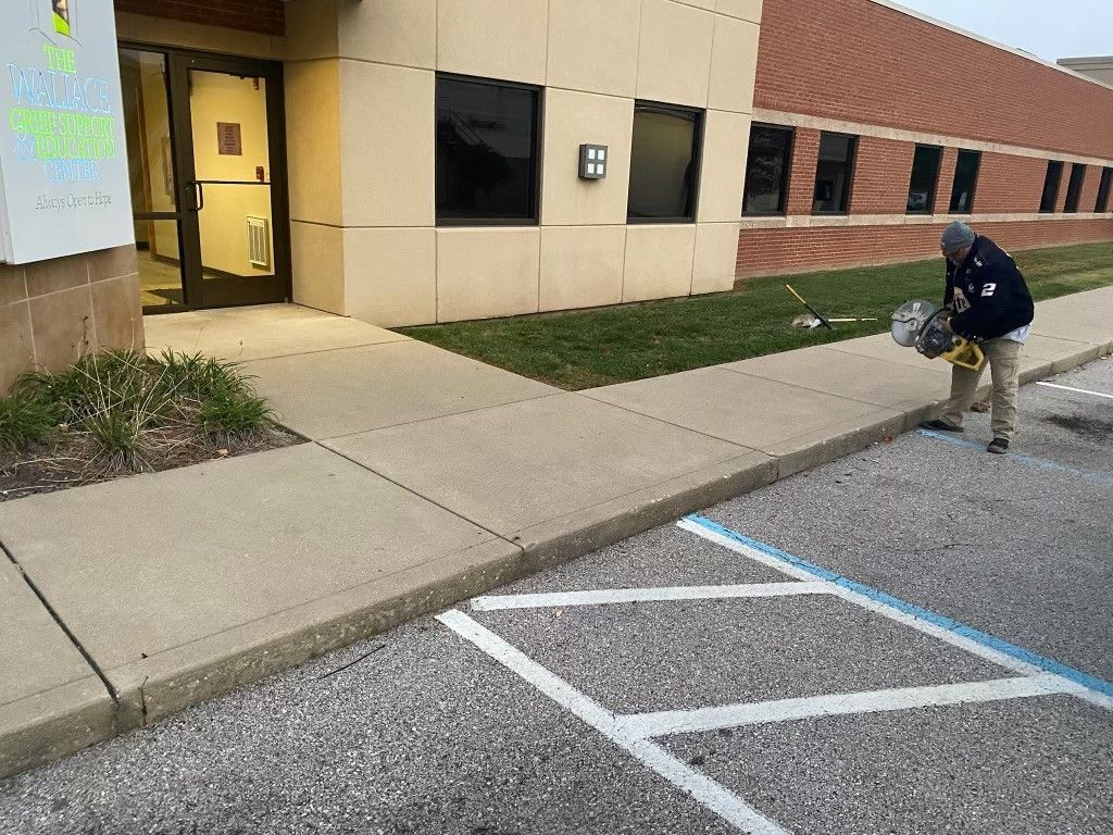 A man is standing in a parking lot in front of a building.