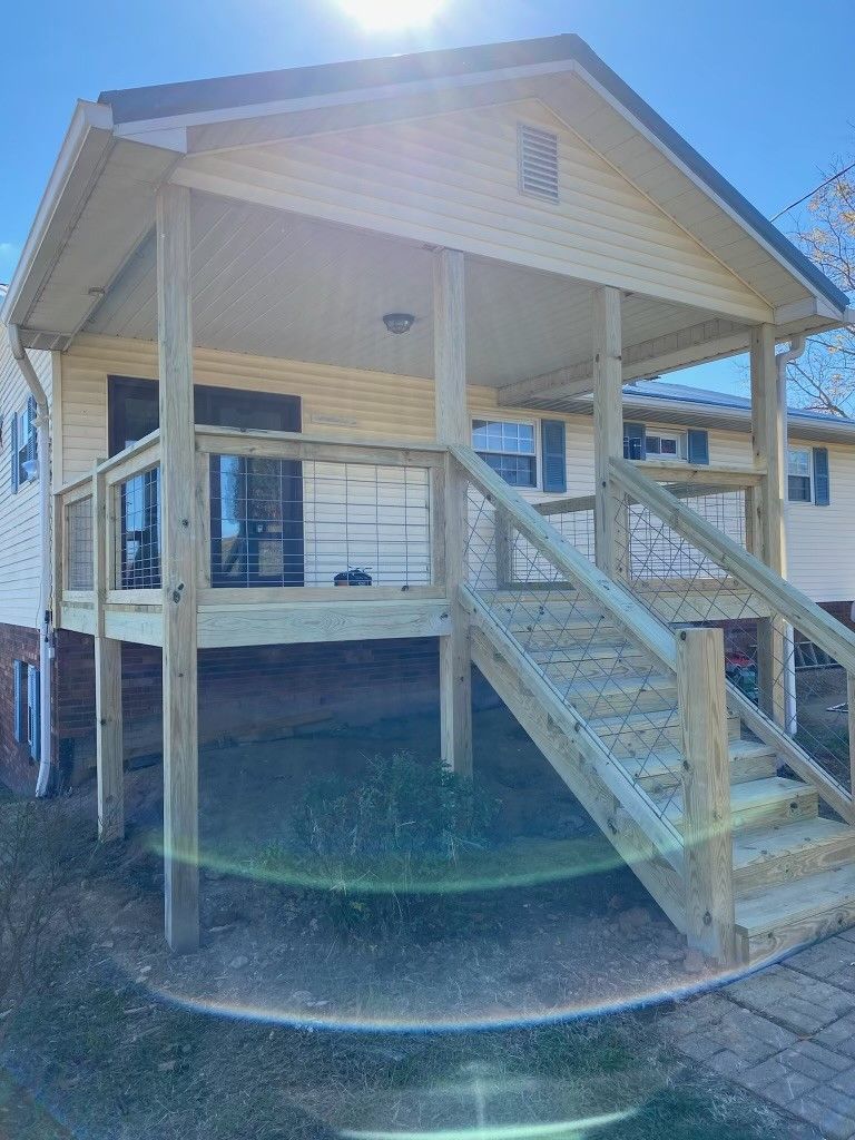 A wooden deck with stairs leading up to it is in front of a house.