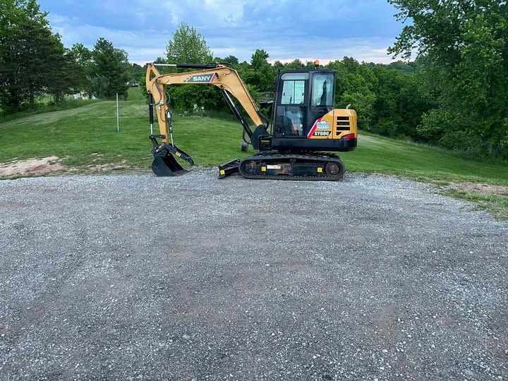 A small excavator is parked in a gravel lot.