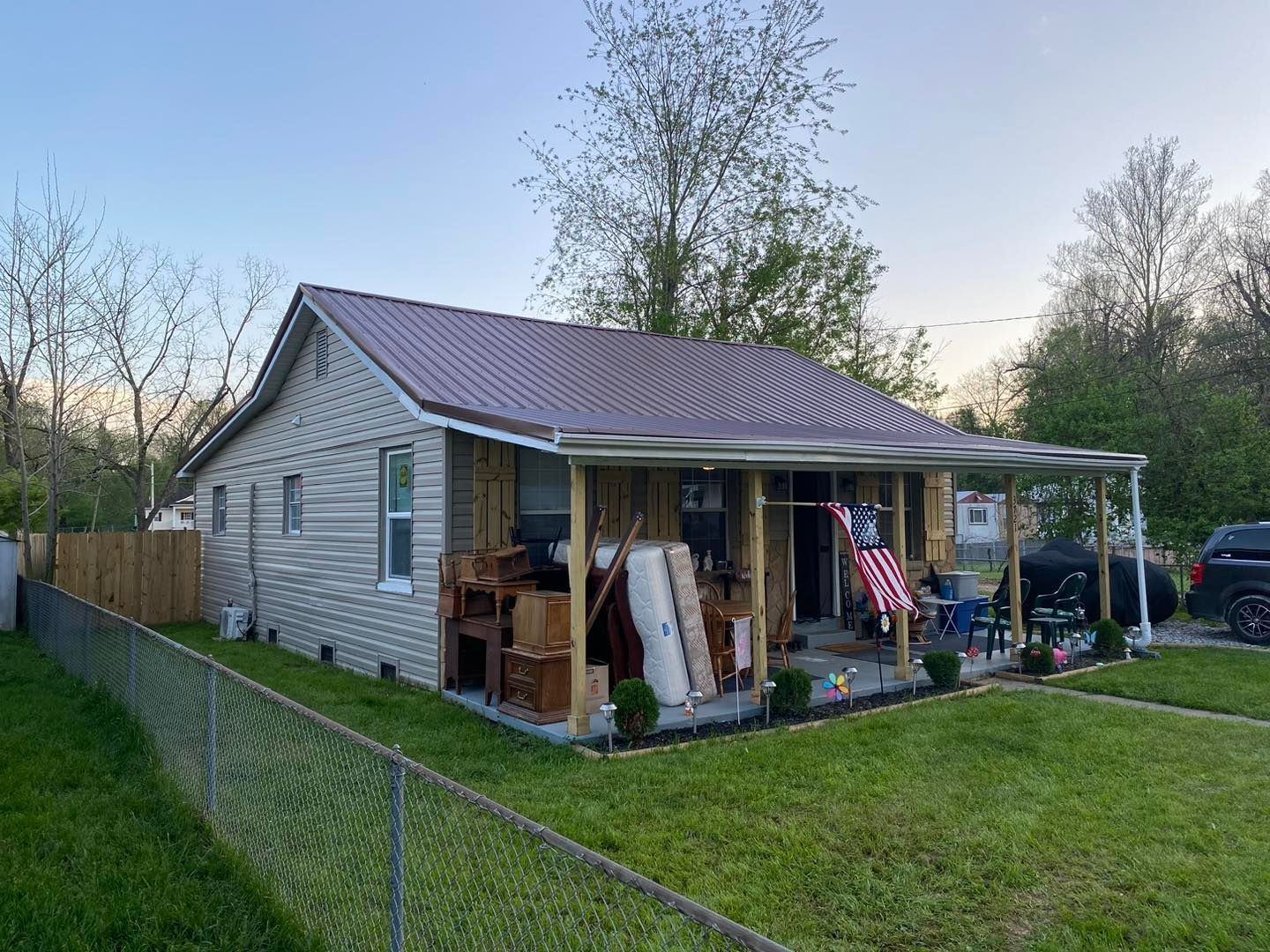 A small house with a porch and a fence in front of it.