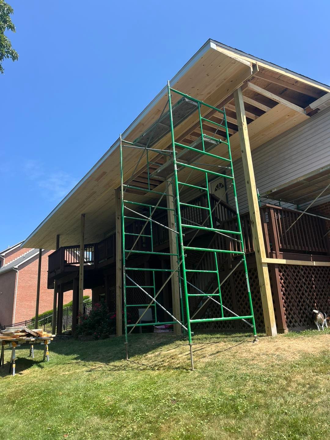 A green scaffolding is sitting in front of a house under construction.