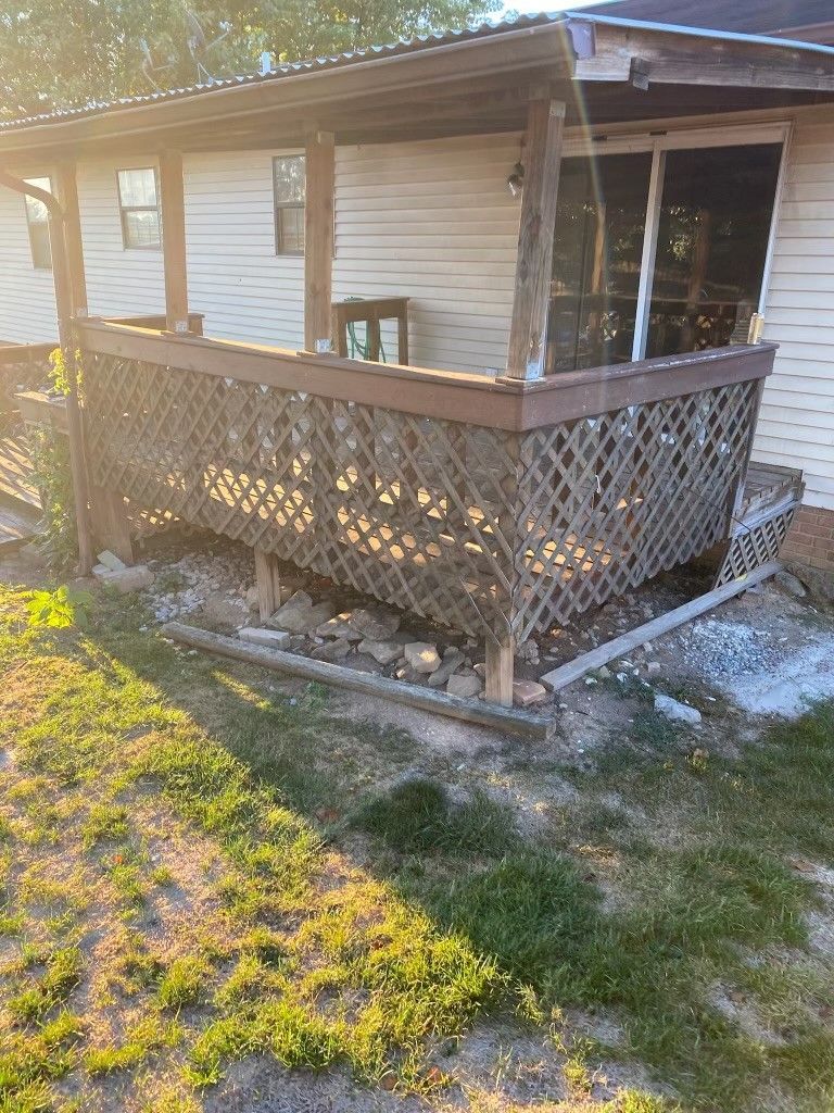 A house with a porch and a fence in front of it.