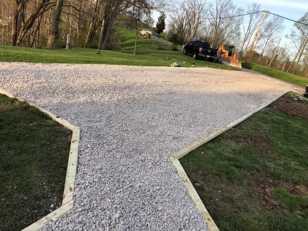 A gravel driveway with a truck parked on the side of it.