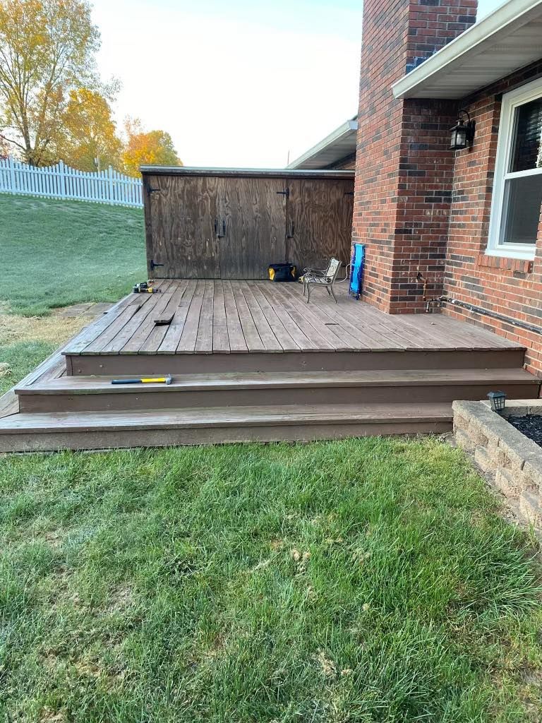 A wooden deck is being built in front of a brick house.
