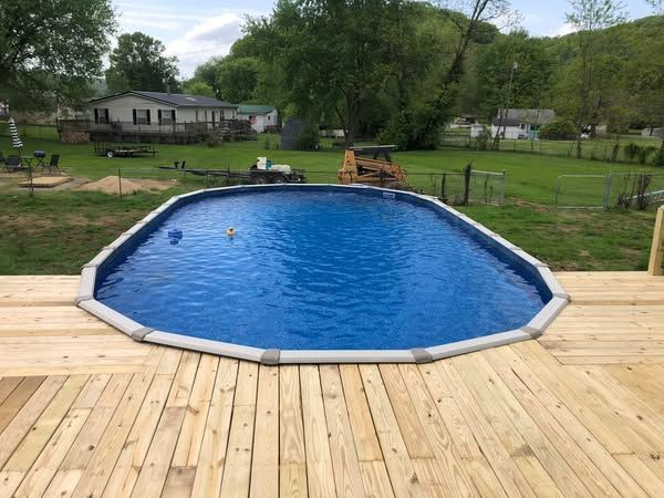 A large swimming pool is sitting on top of a wooden deck.