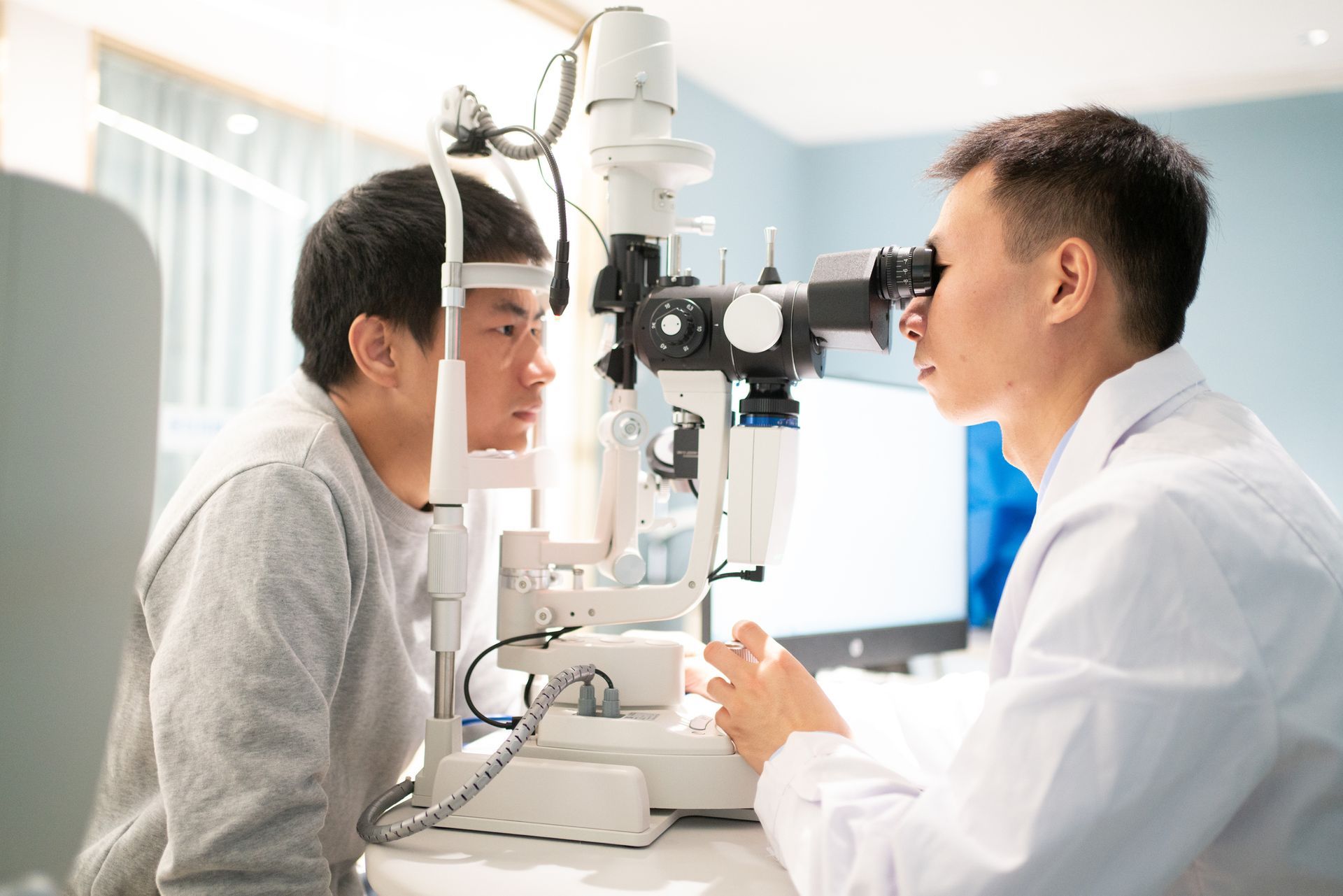 A male ophthalmologist using slit lamp to inspect patient's vision.