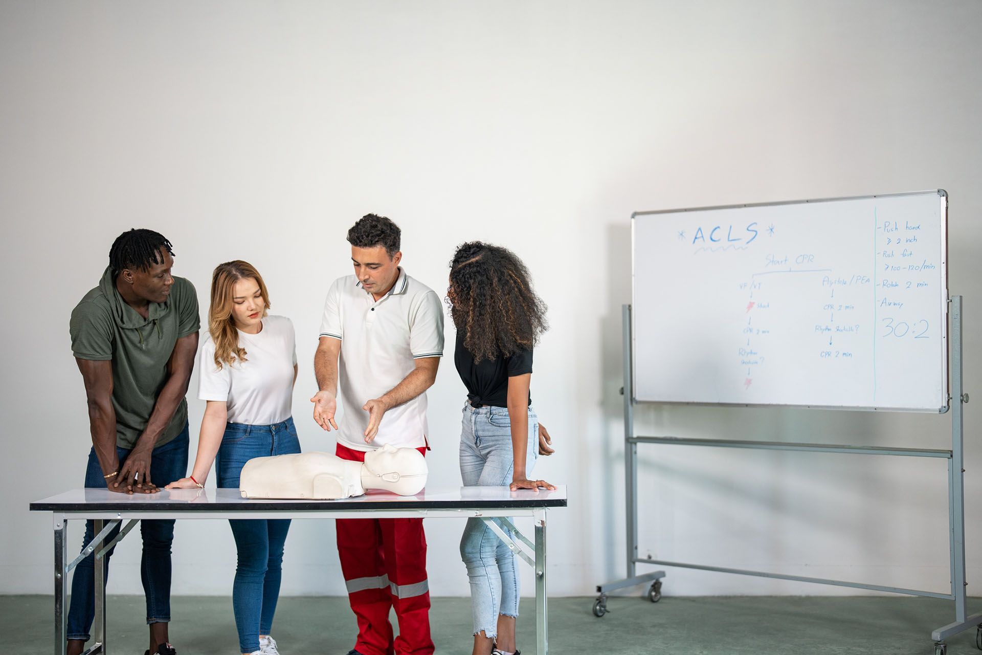 A group of people is standing around a table looking at a mannequin
