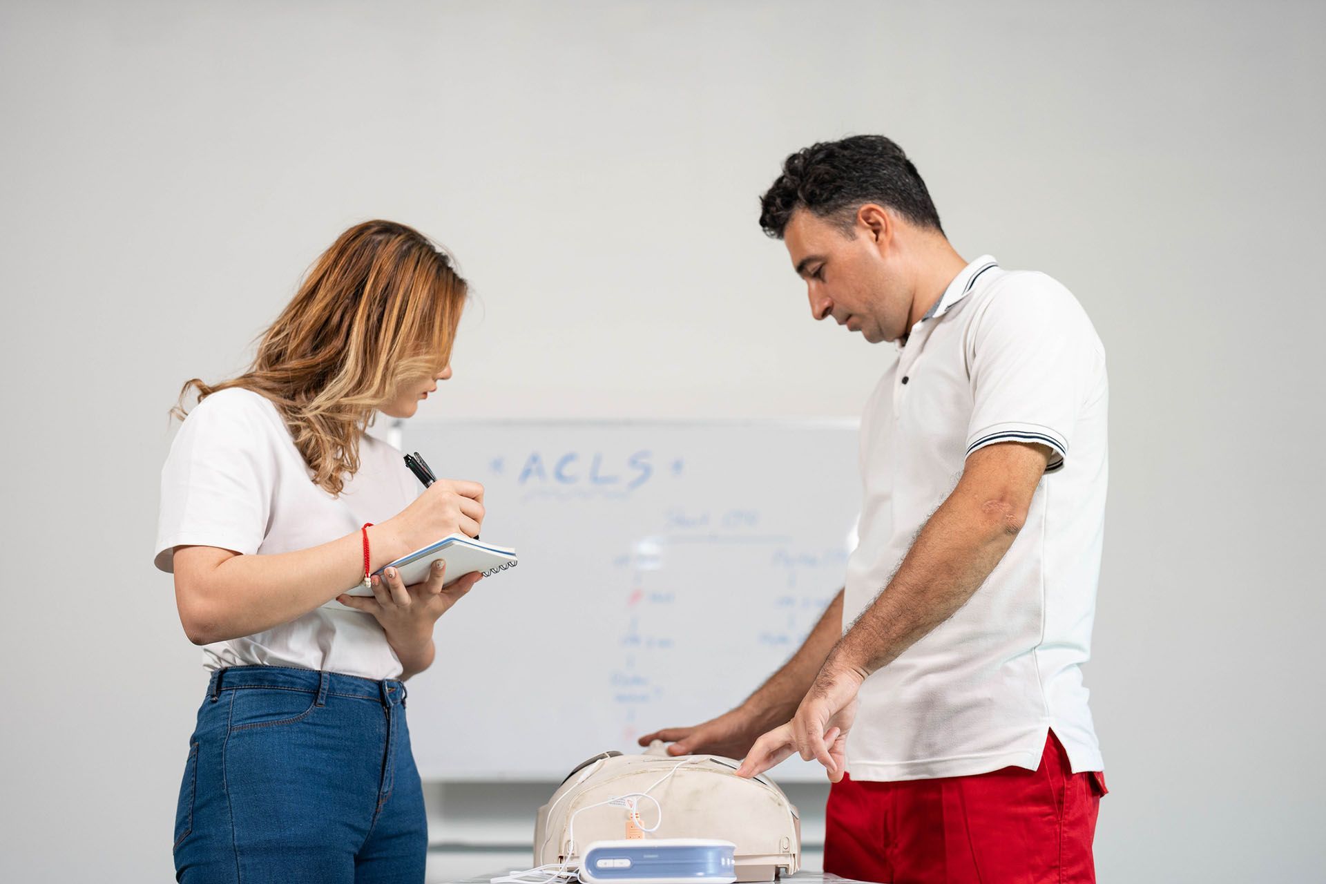 A man and a woman are standing next to each other in front of a whiteboard
