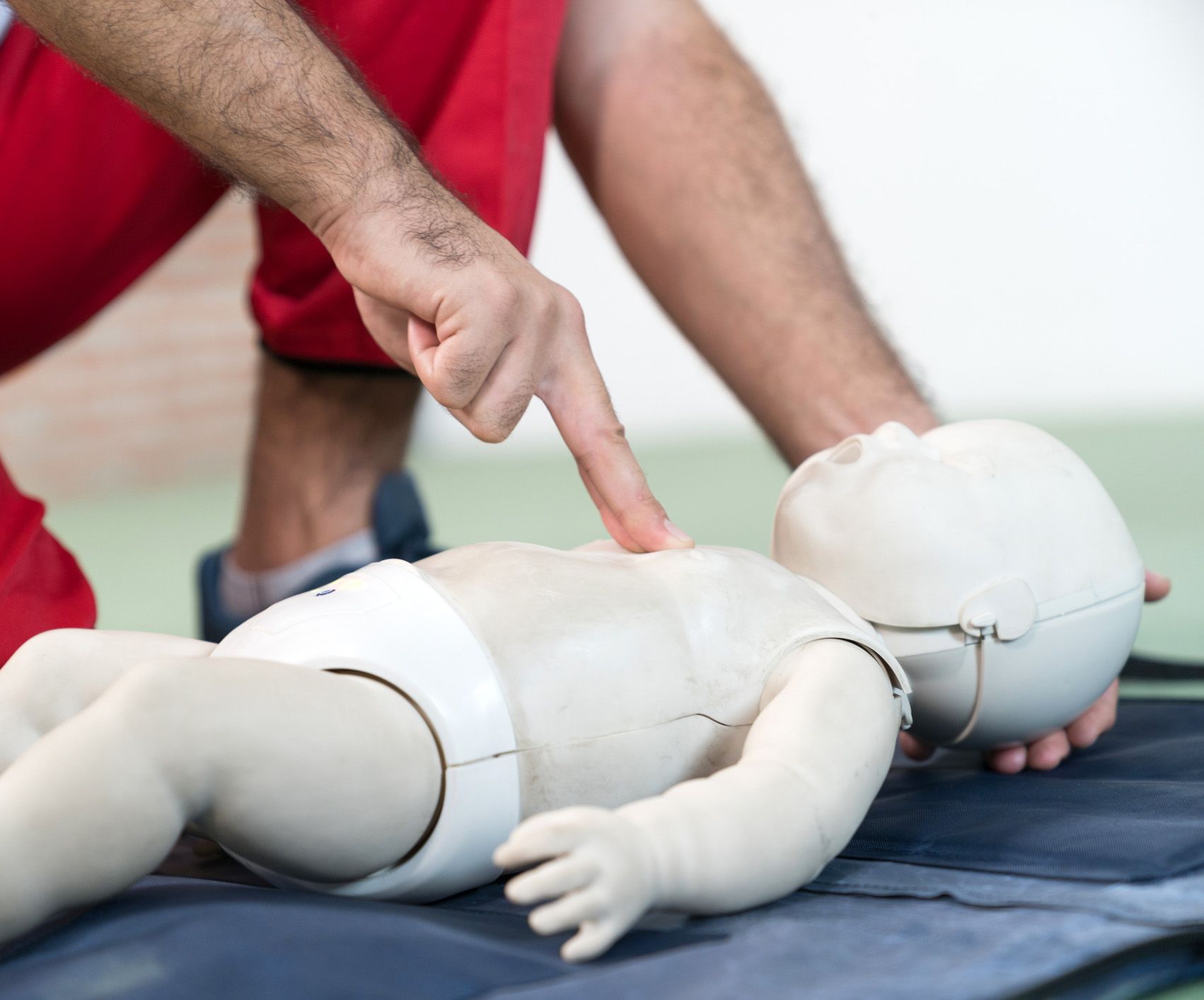A man is pointing at a baby mannequin with his finger