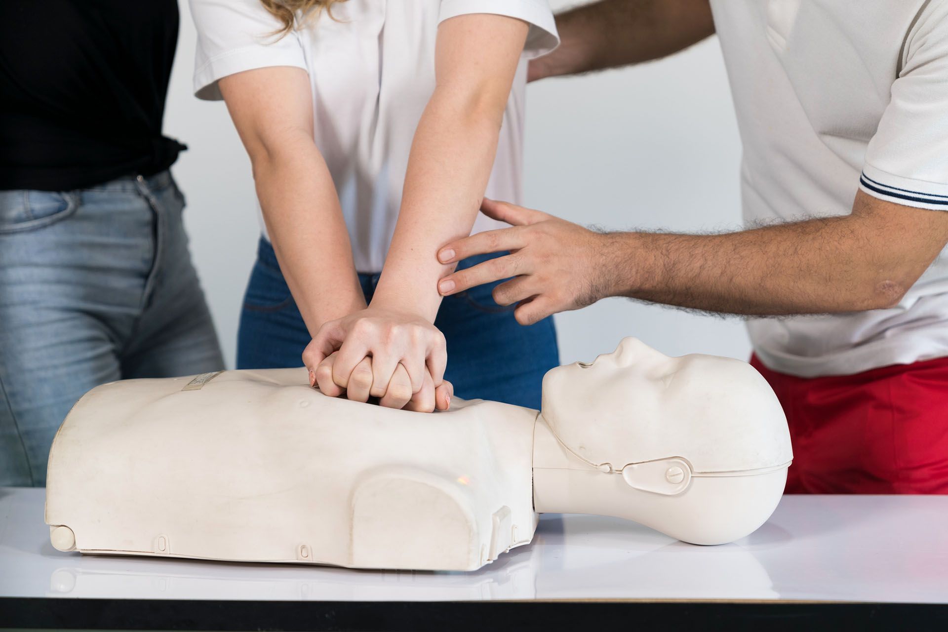 A group of people is practicing first aid on a mannequin