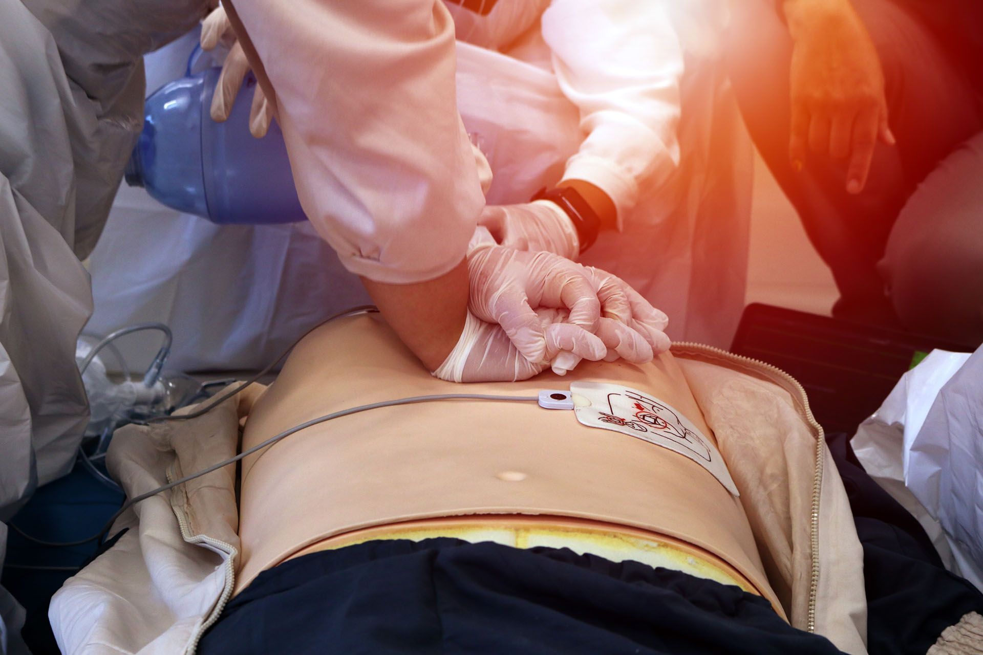 A mannequin is lying on a stretcher with a defibrillator on his chest