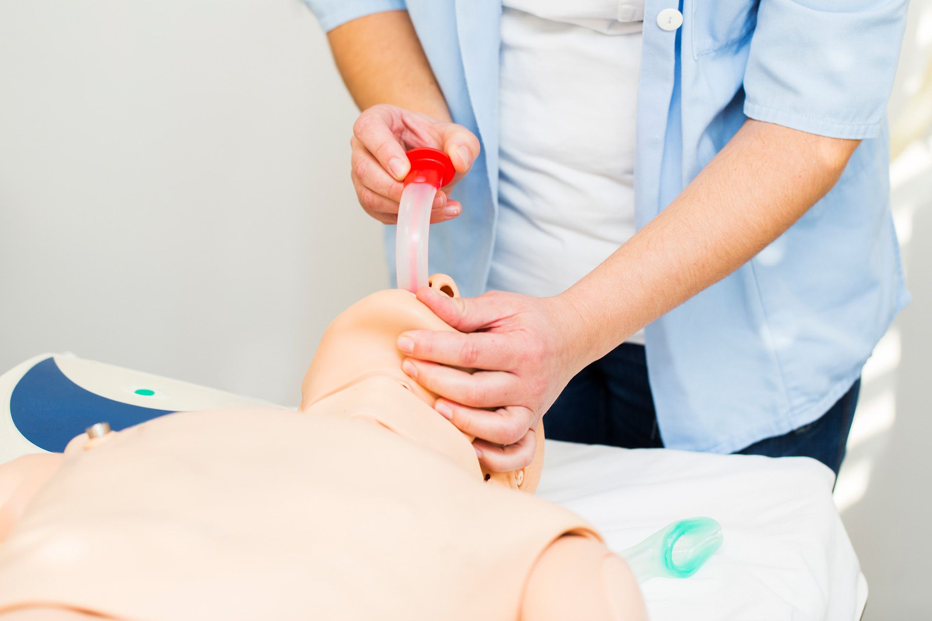 A nurse is putting a tube into a mannequin's mouth