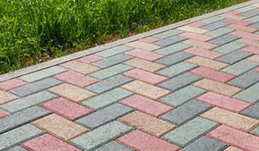 a brick walkway with a grassy sidewalk in the background .