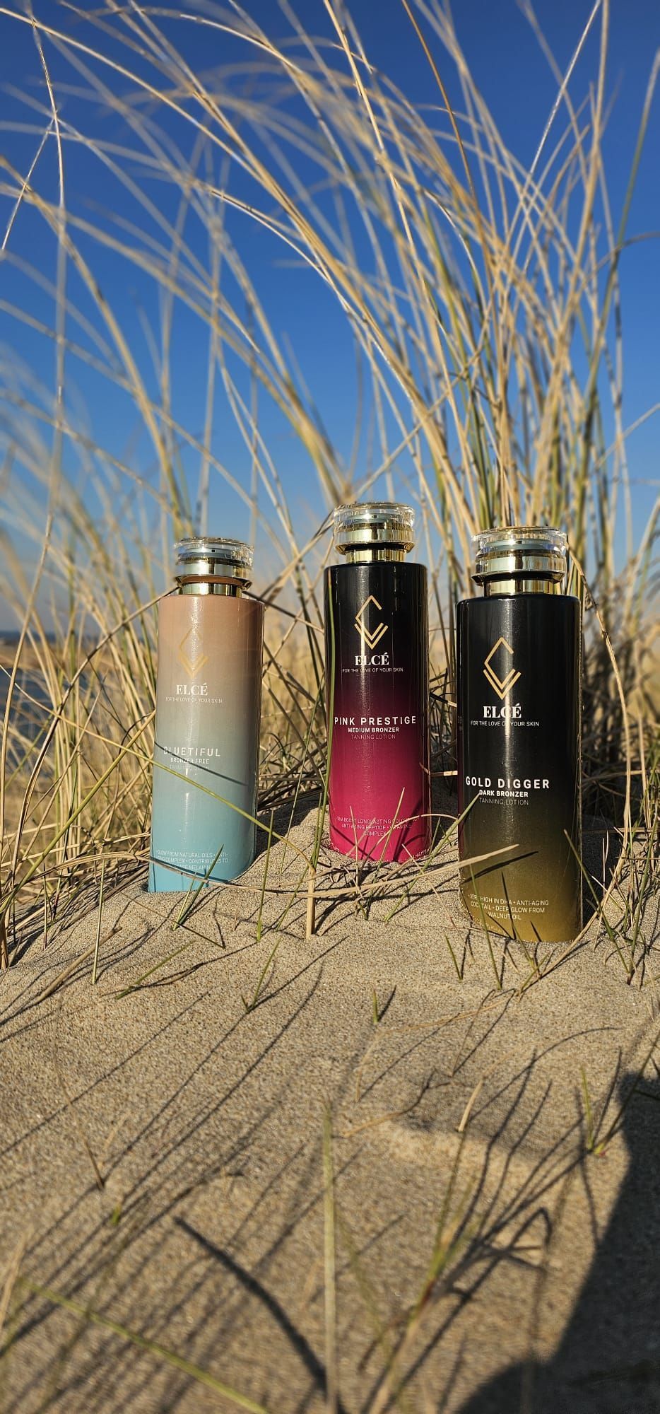 Drie flesjes parfum staan op een zandstrand.