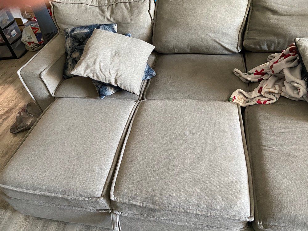 Triple I LLC | a couch with pillows and a blanket on it in a living room.