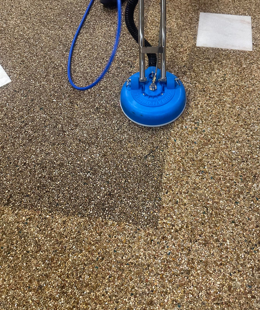 Blue carpet cleaning machine in action on a carpet, removing dark stains.