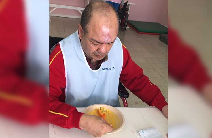 Un hombre está sentado en una mesa comiendo comida de un tazón.