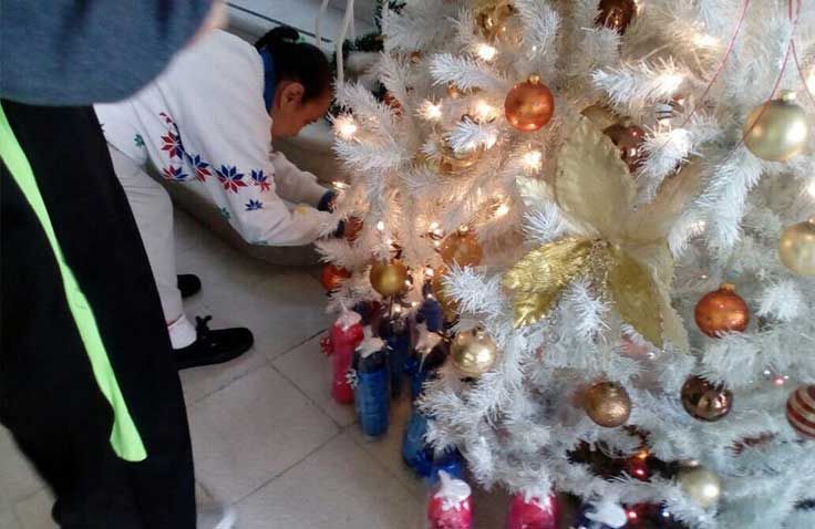 Una persona está decorando un árbol de Navidad blanco con bolas y luces.