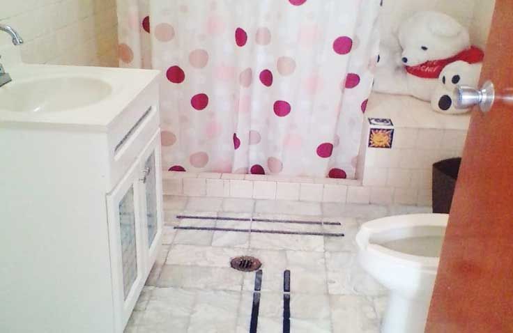 Un baño con una cortina de ducha de lunares y un inodoro.