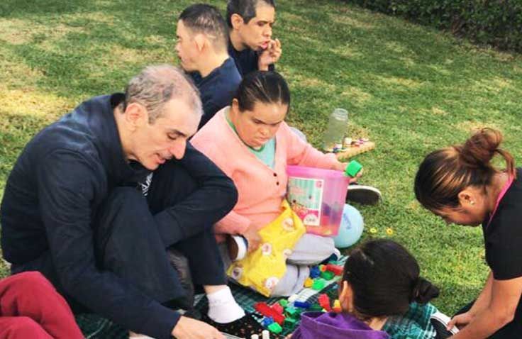 Un grupo de personas está sentada en el césped jugando con juguetes.