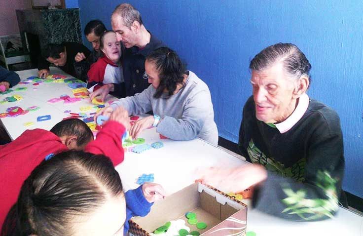 Un grupo de personas están sentadas alrededor de una mesa jugando con juguetes.