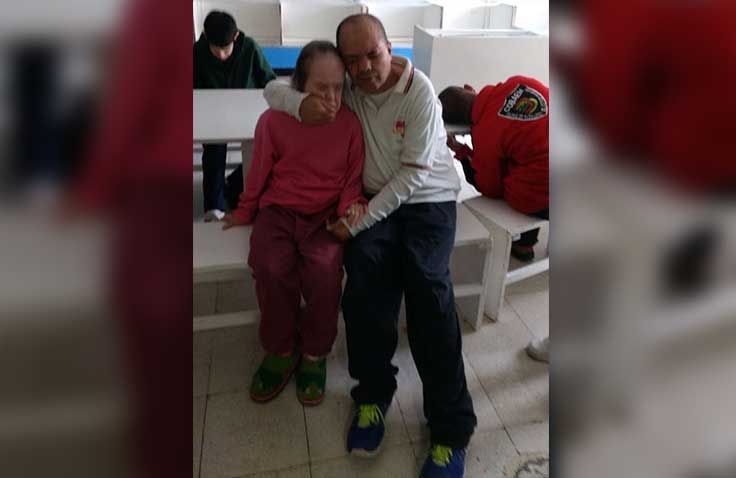 Un hombre y una mujer están sentados en un banco tomados de la mano.