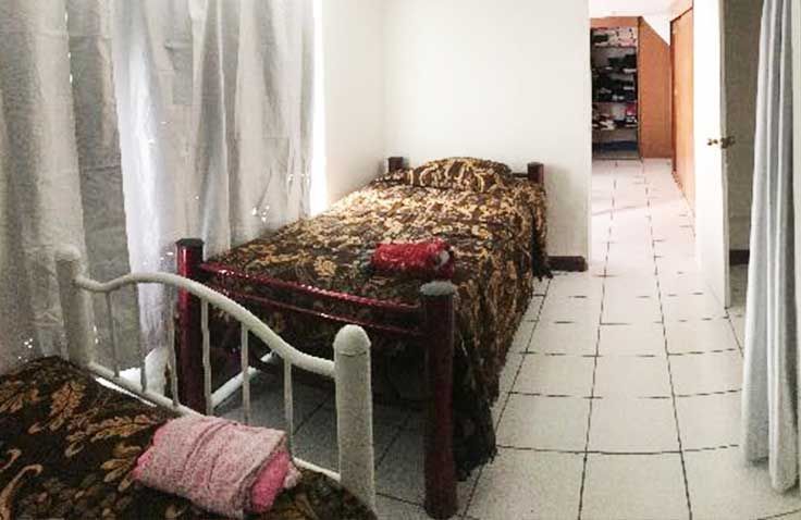 Un dormitorio con dos camas y una puerta que da a un pasillo.