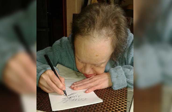 Una mujer está escribiendo en un trozo de papel con un bolígrafo.