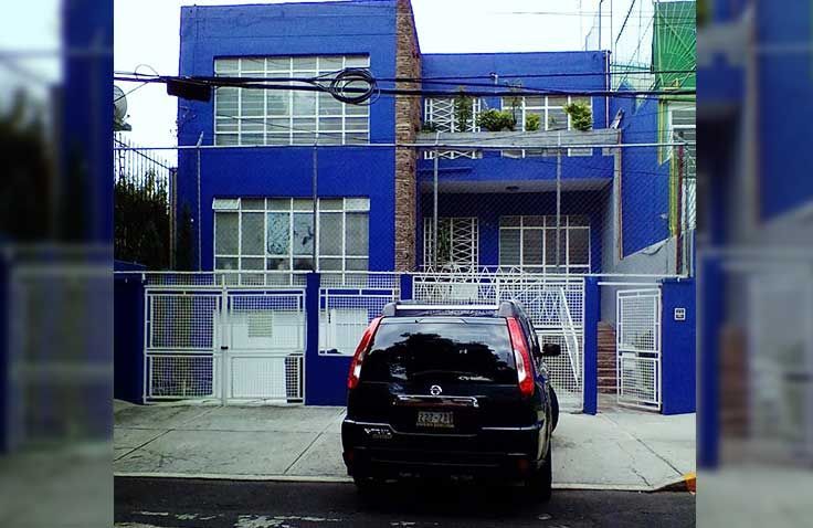 Un coche está aparcado delante de un edificio azul.