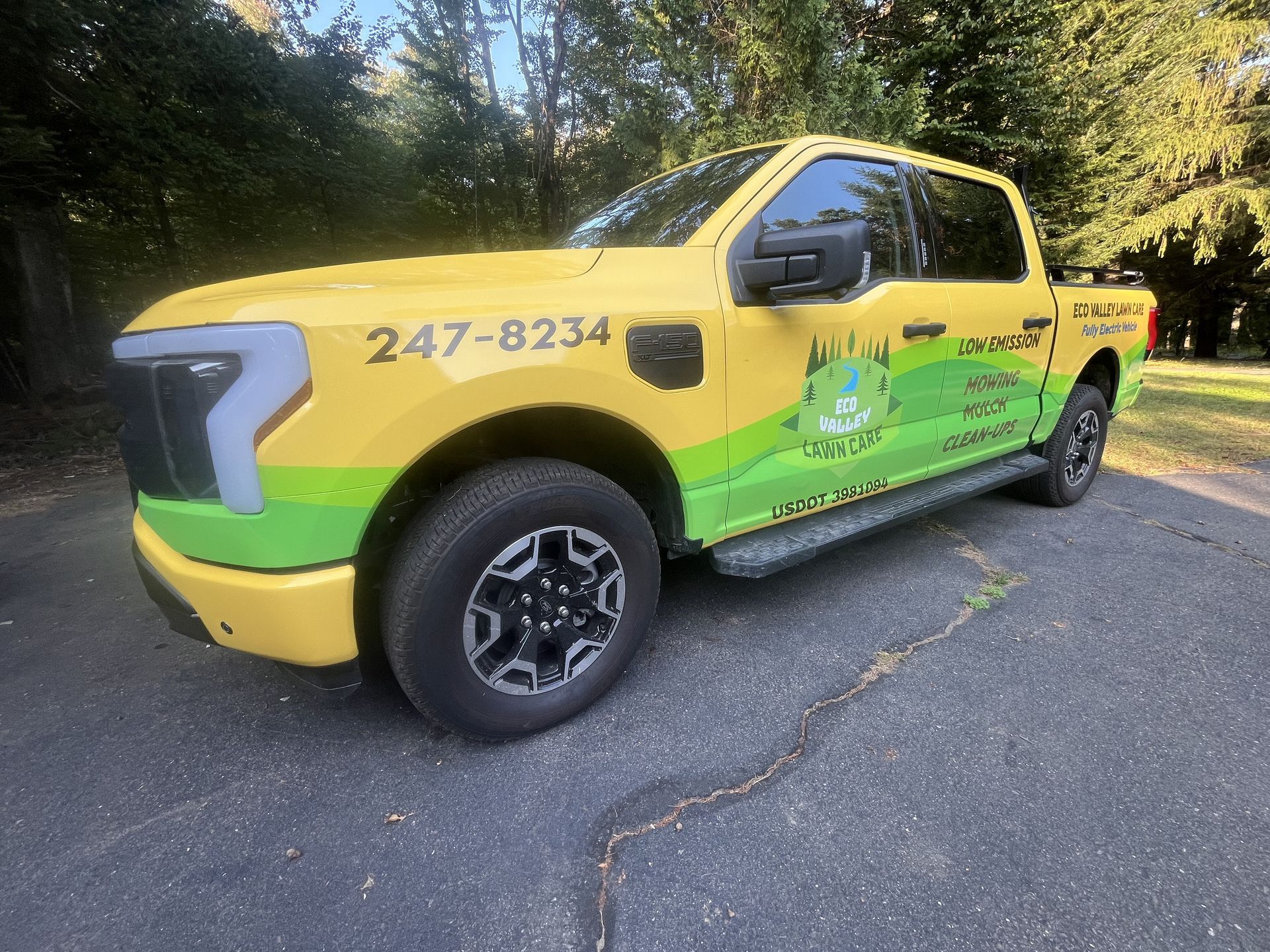 Yellow and green pickup truck with company logo parked on asphalt.
