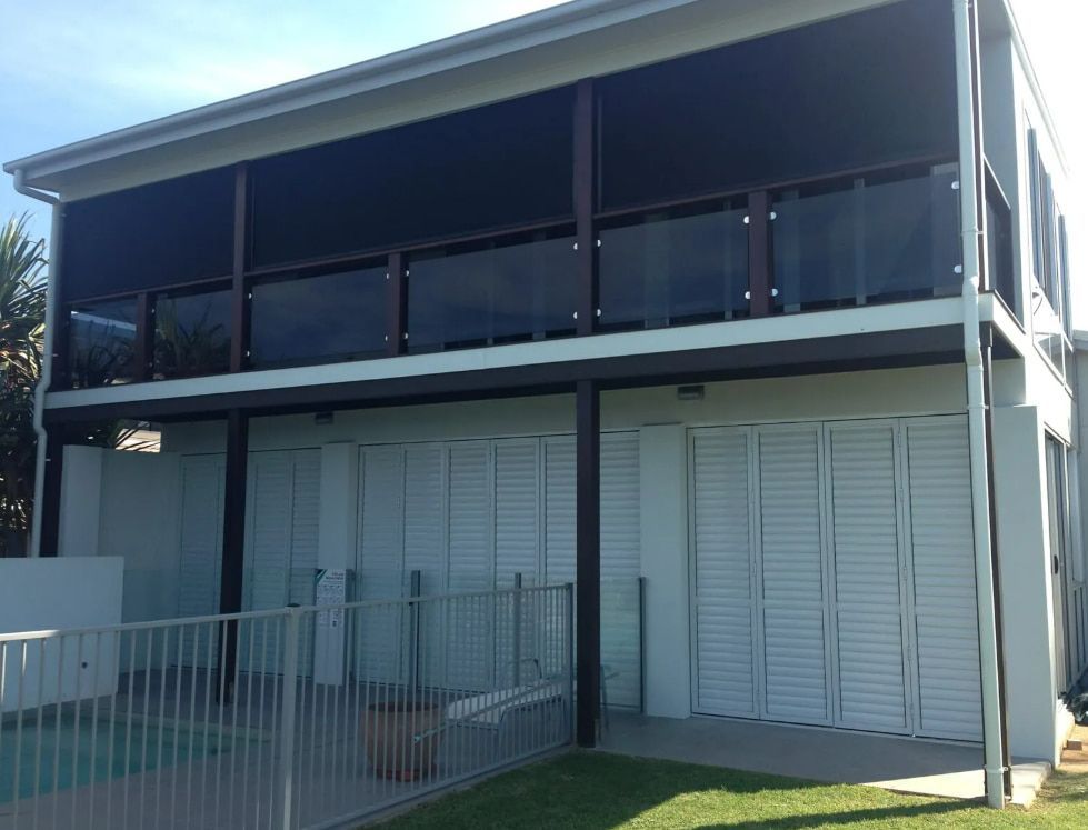 A House With A Fence And A Swimming Pool In Front Of It — Coastal Blind Installations In Kensington, QLD